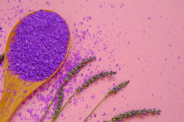 lavender salt.Cosmetic lilac salt with lavender extract in wooden spoon and lavender flowers on a pink background.purple sea bath salt . Flower bath salt.Aromatherapy and spa.body cosmetic 