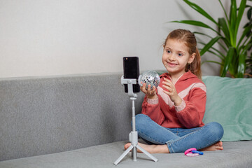 Small blonde blogger girl, an influential person, communicates with subscribers, conducts a live broadcast with a cat, looks at the smartphone screen at home. When taking a selfie, call your friends.