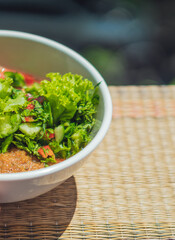 VERTICAL Ceramic white light bowl with mix green lettuce leaves, spinach leaf salad ingredients fresh vegetables pureed red tomato serving plate. Healthy vegan food cuisine. Close-up View from above