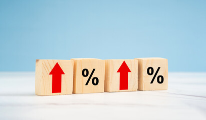 Finance and interest rate concept. Wooden cubes with arrows up and percentage symbol over a blue...