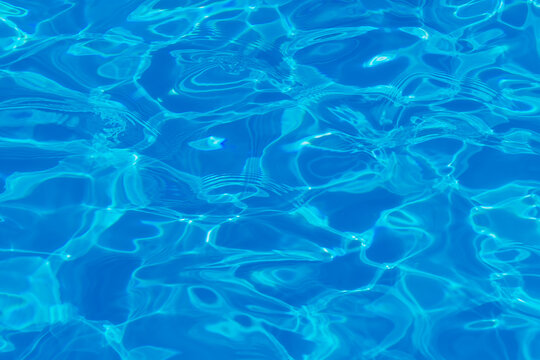 Swimming pool water surface with sparkling light reflections. Aqua background.