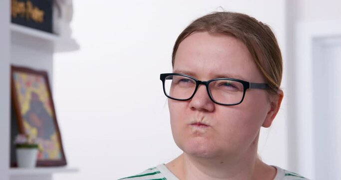 Portrait of young woman with glasses, who looks with shock and discouragement at mess, turns head and sees culprit of what happened, so she squints eyes viciously and vindictively