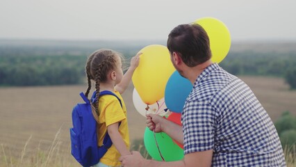 little child girl with her father plays colorful balloons inflated with helium. happy family park....