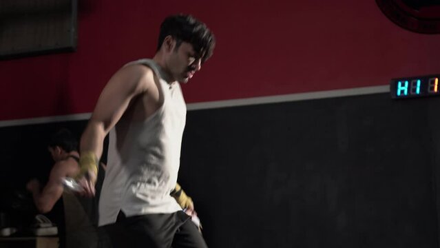 Handsome young man is skipping with jumping rope in fitness gym, Sportsman exercising at gym