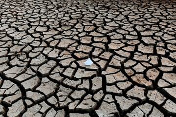 White paper boat on dry, dry soil with cracks. Global warming concept