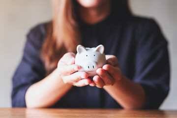 Closeup image of a woman holding a piggy bank for saving money and financial concept - obrazy, fototapety, plakaty