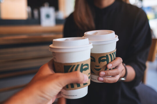 Jun 13th 2022 : Closeup of a couple people holding and clinking two cup of hot coffee at Starbucks coffee shop, Chiang mai Thailand