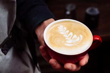 Barista holds a cup of latte coffee.