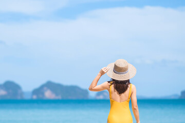 Woman tourist in yellow swimsuit and hat, happy traveler sunbathing at Paradise beach on Islands. destination, wanderlust, Asia Travel, tropical summer, vacation and holiday concept