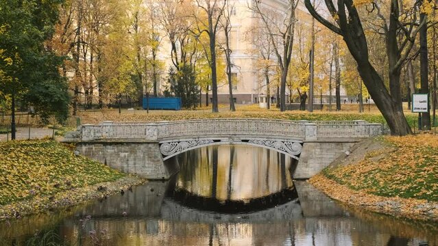 Scenic view of stone bridge and small river under it in autumn city park. Fall season concept