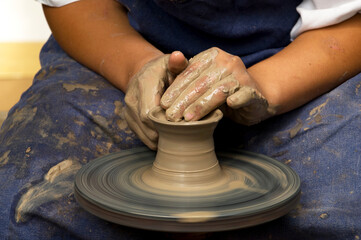 Potter modeling ceramic pot from clay on a potter's wheel. Workshop, art concept