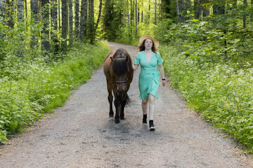 Icelandic horse on gravel road with young woman. Shot in the evening middle of the summer in Finland