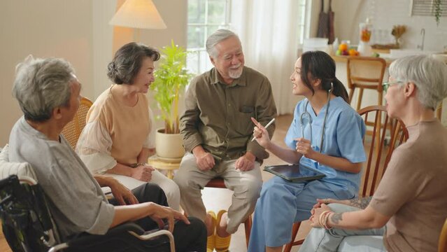 Group of asian senior people listening to young nurse.Psychological support group for elderly therapy session in a community centre. Group therapy in session sitting in a circle in a nursing home.