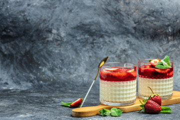 Dessert Panna Cotta with fresh strawberry in glass with strawberries. Italian dessert on a blue...