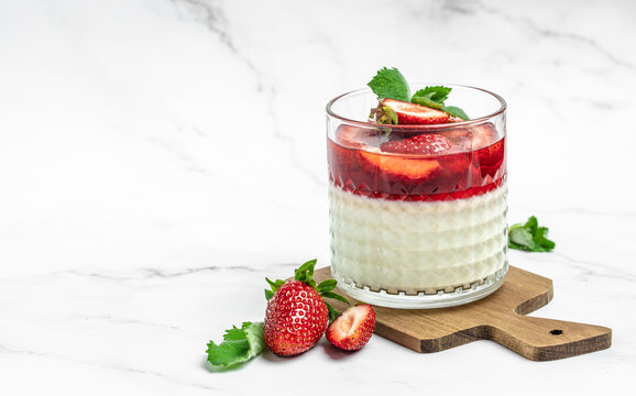 Italian panna cotta dessert with strawberry and mint on a light background. Summer yogurt dessert. space for text