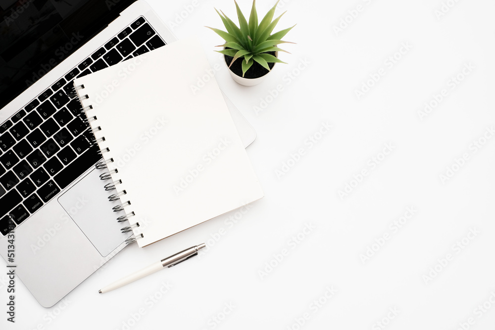 Wall mural blank white notepad and laptop computer with stationery on white table desk background with copy spa