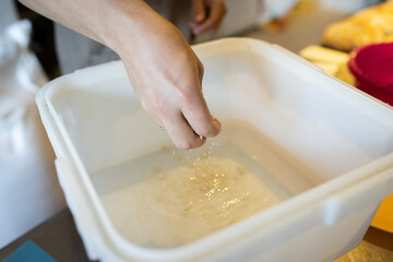 The process of making wheat bread. Adding yeast to the water before kneading. Front view.