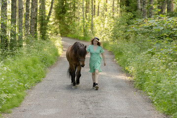 Icelandic horse on gravel road with young woman. Shot in the evening middle of the summer in Finland