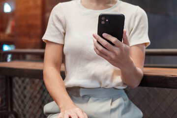 Casual Businesswoman holding and using smartphone for sms messages, young woman typing touchscreen mobile phone in cafe or modern office. lifestyle, technology, Social media and network concept