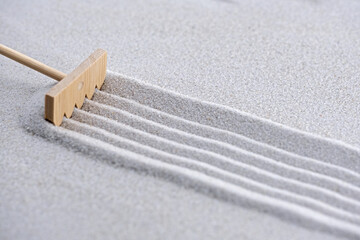 pattern in the sand with zen garden tool, a rake