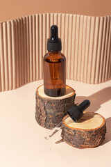 Glass dropper bottle with cosmetic serum on wooden stump podium with hard shadow. Hyaluronic acid...