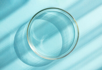 empty glass petri dish on a blue background with rays of sunlight