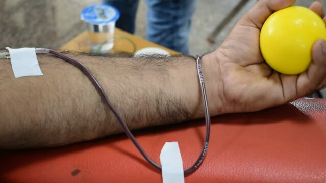 Blood donor at Blood donation camp held with a bouncy ball holding in hand at Balaji Temple, Vivek Vihar, Delhi, India. Also concept image for World blood donor day on June 14 every year