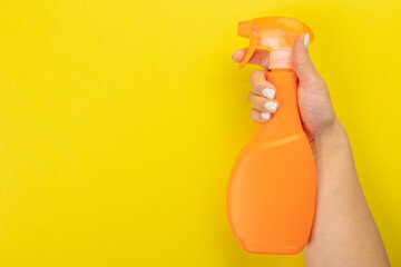 Cleaner's hand holding a  chemical spray bottle. Empty space for text or logo on a yellow...
