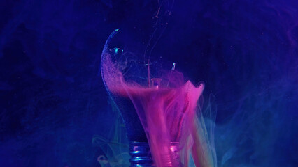 Ink water drop. Broken light bulb. Fantasy energy. Neon pink blue color smoke haze floating in...