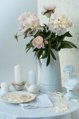 Table setting with a cup of tea and white peonies in a white ceramic jug