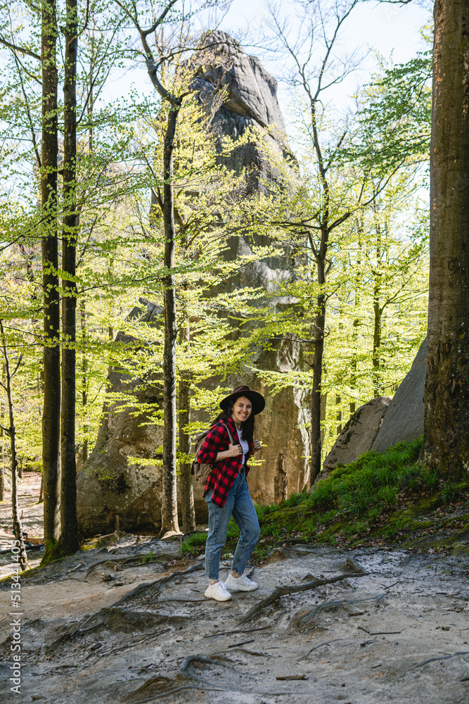 Wall mural woman hiker with backpack walking by forest trail