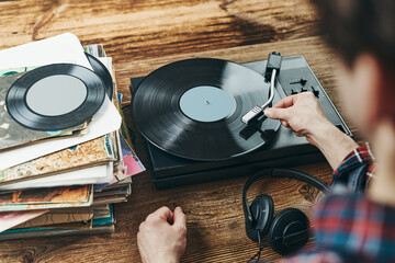 Man listening to music from vinyl record. Playing music from analog disk on turntable player. Enjoying music from old collection. Retro and vintage - Powered by Adobe