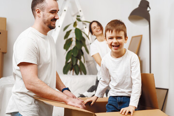 Obraz premium Parents and son packing boxes and moving into a new home