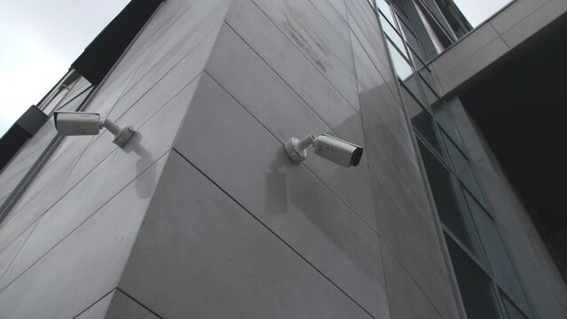 Surveillance cameras on tiled walls of contemporary office center on city street low angle shot. Security equipment