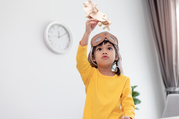 Asian little girl at home plays with a toy plane, she wants to become a pilot. Dreamer pilot. © FAMILY STOCK