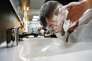 Hairdresser man washes client head in barbershop, close up