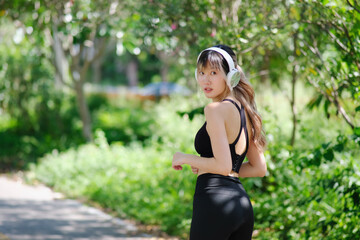 Woman wearing earphones listening to music while running on a mountain trail in the morning. female wearing gym wear jogging alone in nature