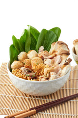 Boiled instant noodles in a large white bowl isolated on white background. This bowl of noodles consisting of instant noodles, seasoning powder, meatballs, pork, and vegetables. popular fast food.