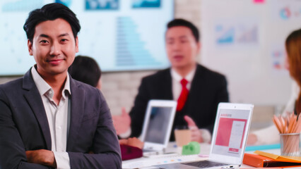 Confident young businessman sitting smiling at the camera in a meeting room.