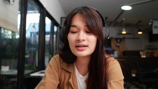 Close up shot, pretty teenage sitting and enjoy to listening musice from wireless headphone and singing together, lifestyle concept