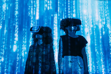 Digital code falling on boy and girl wearing virtual reality simulator