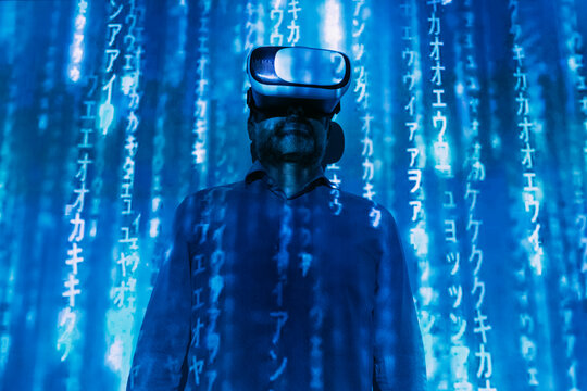 Digital code falling on man wearing virtual reality simulator in front of wall