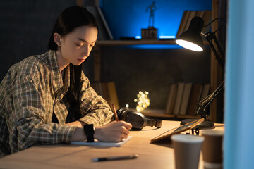 Asian serious girl is studying online via the internet on tablet digital while sitting at home at night. online learning at home