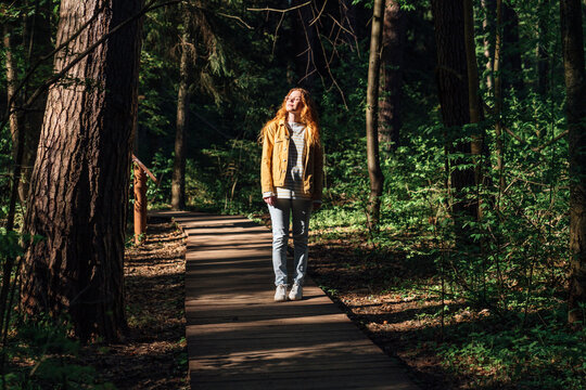 Young woman with eyes closed walking on footpath in forest