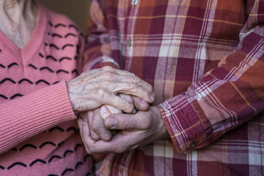 Senior woman holding hands of mature man at home
