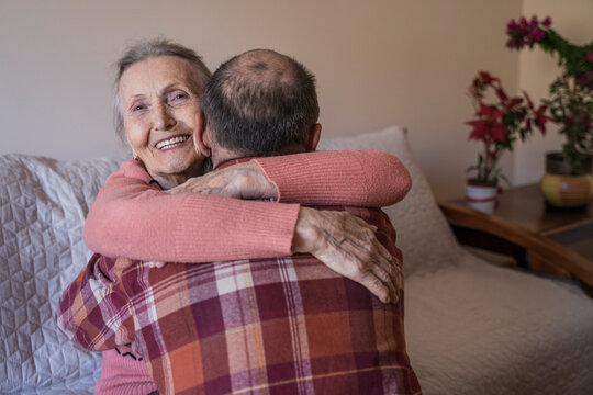 Happy senior woman hugging mature man at home