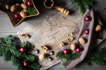 Studio shot of cutting board, star shaped wicker basket, twigs, Christmas ornaments, walnuts and simple nutcracker