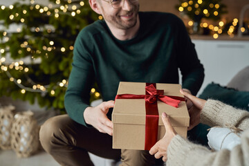 Smiling man giving gift to woman at home