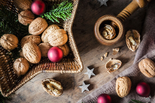 Studio shot of cutting board, star shaped wicker basket, Christmas ornaments, walnuts and simple nutcracker