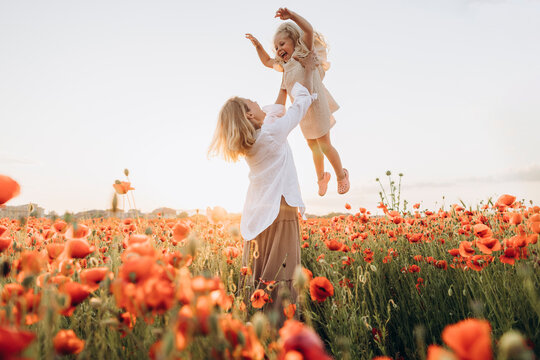 Playful mother lifting daughter in air on sunny day